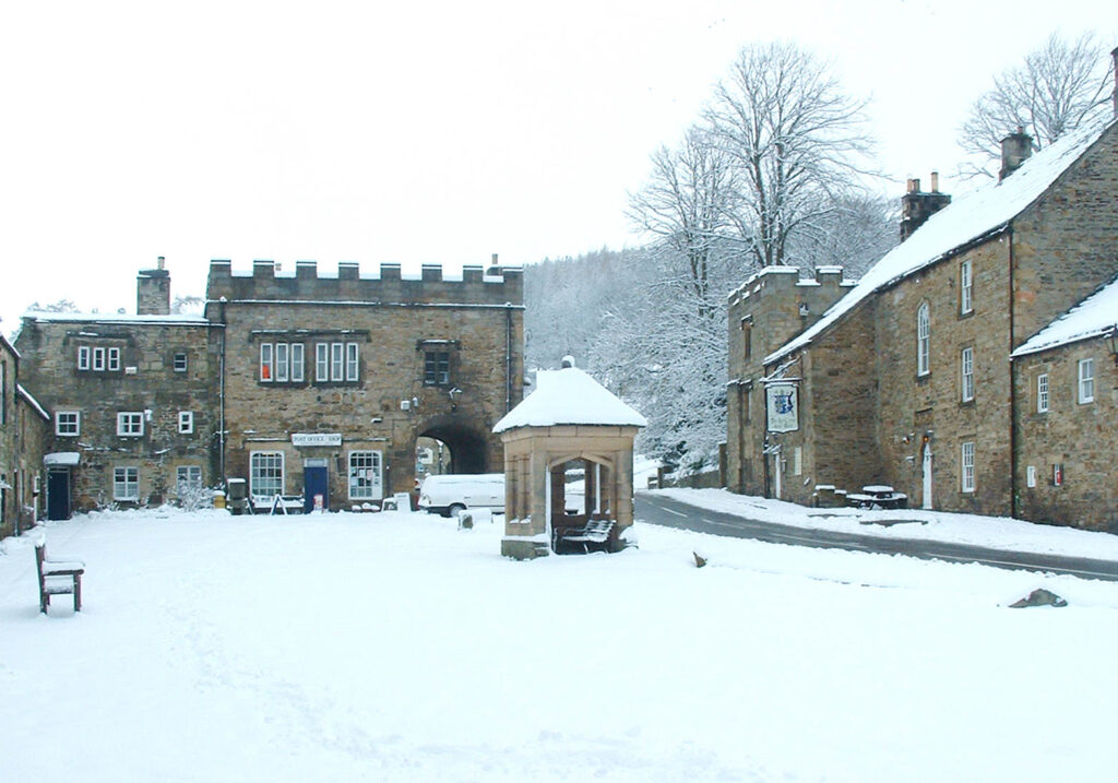 Snowy scene of historic buildings surrounding the village square